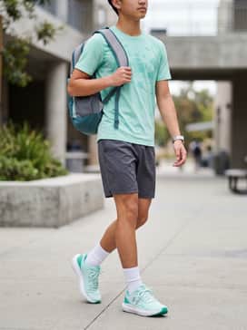 A performance-focused outfit featuring charcoal grey moisture-wicking shorts and a mint green graphic t-shirt to echo the shoe's primary color.