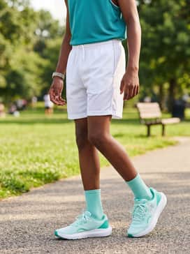 A bright summer look pairing white mesh basketball shorts with a sleeveless teal jersey and matching crew-length athletic socks.