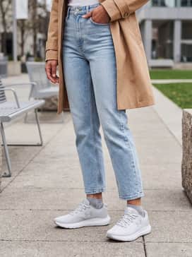 Light-wash cropped straight-leg jeans with a tucked-in pastel graphic tee and a lightweight tan trench coat for an elevated casual weekend ensemble.