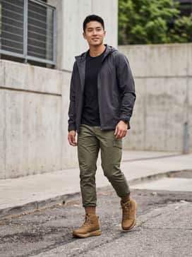 Tapered olive green ripstop cargo pants paired with a black oversized technical hoodie and a charcoal hardshell rain jacket.
