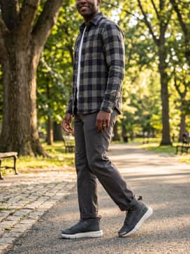 Straight-leg charcoal work trousers, a flannel button-down shirt layered over a white tee, and a quilted puffer jacket for a durable weekend ensemble.