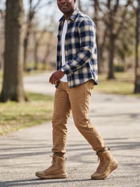 Ua Valsetz – A durable workday style pairing heavy-duty tan canvas work pants with a classic navy blue and cream flannel shirt layered over a simple white crewneck t-shirt.