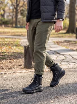 Heavyweight olive drab fatigue pants, a black mock-neck base layer, and a quilted insulated jacket for cold-weather adventures or field work.
