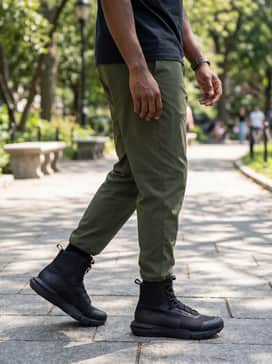 Ua Valsetz Wide 4e – An outdoor adventure style pairing olive green moisture-wicking hiking trousers with a navy thermal henley and a quilted down puffer vest.