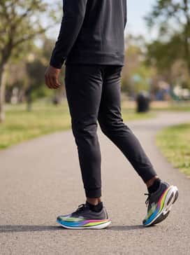 Ua Velociti Elite 3 – A sleek track-side warm-up outfit with tapered black joggers, a quarter-zip tech fleece in light grey, and a matching neon-accented sports cap.