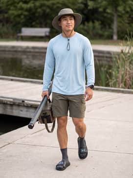 A performance-driven fishing outfit including olive drab quick-dry cargo shorts, a light blue UV-shielding long-sleeve shirt, and a wide-brimmed sun hat.
