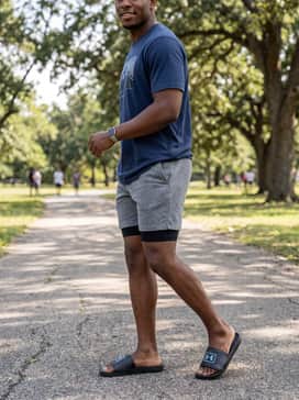 Ua X Blacktiph Fish Armr – A relaxed weekend ensemble pairing light grey jersey lounge shorts with a navy blue graphic t-shirt and a matching blue baseball cap.