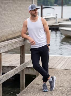 Ua X Blacktiph Fish Kilchis – Black lightweight joggers, a breathable white mesh tank top, and a sporty baseball cap for a trail walk.