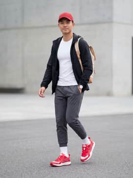 A sleek performance look featuring charcoal grey tapered joggers, a white moisture-wicking compression tee, and a matching red baseball cap to tie in the shoe color.