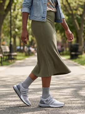 A ribbed olive green midi skirt, a tucked-in vintage graphic t-shirt, and an unbuttoned denim jacket to balance sporty functionality with feminine style.