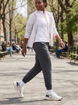 Ultraboost 5 Shoes – Charcoal grey tapered joggers and a fitted white running jacket with orange accents that mirror the branding on the shoes for a sleek athletic finish.