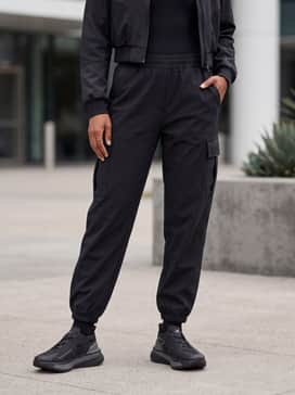 Oversized black cargo joggers and a fitted rib-knit bodysuit topped with a cropped technical bomber jacket for an edgy urban street look.