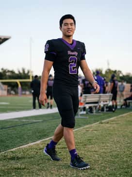 Ultraboost Football Cleats – A coordinated team uniform consisting of a black jersey with purple numbering and matching padded football pants for a sleek professional look.
