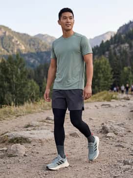Ultrarun 5 Tr Running Shoes – A high-performance trail outfit consisting of black compression leggings, charcoal moisture-wicking shorts, and a breathable sage green running tee.