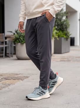Ultrarun 5 Tr Running Shoes – A casual urban explorer look with tapered charcoal cargo pants, a cream-colored hoodie, and a lightweight technical windbreaker in olive.