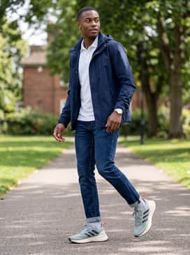 Ultrarun 5 Tr Running Shoes – A practical commute outfit with dark-wash tapered jeans, a crisp white performance polo shirt, and a navy utility jacket.