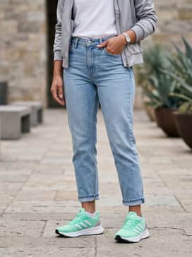 A casual weekend ensemble consisting of light-wash cropped straight-leg jeans, a crisp white tucked-in t-shirt, and a silver-grey bomber jacket that complements the metallic heel counter.
