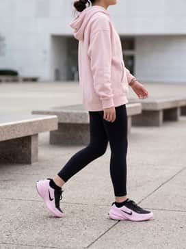 Black moisture-wicking leggings paired with a light pink oversized hooded sweatshirt and a sleek black headband for a coordinated gym-ready look.