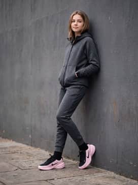 A charcoal grey tech-fleece tracksuit with the pants tapered at the ankles to highlight the shoes, perfect for a comfortable travel or weekend ensemble.