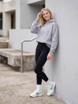 A modern athleisure outfit with high-waisted black 7/8 leggings, a grey oversized hoodie, and sleek white crew socks to bridge the gap between shoe and leg.
