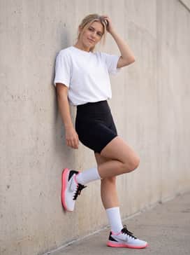 Black high-rise bike shorts styled with an oversized white graphic t-shirt and tall white crew socks to highlight the sneaker's bold pink sole.