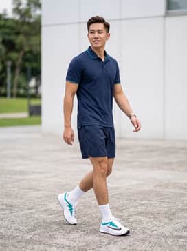 A professional tennis look featuring a white moisture-wicking polo with teal trim, navy blue athletic shorts, and high-performance white crew socks.