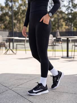 A sleek gym look consisting of high-waisted black compression leggings, a cropped long-sleeve athletic top in white, and a matching headband for a coordinated fitness vibe.