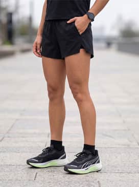 Velocity Nitro 3 Goretex Womens Running Shoes – Black performance-tech shorts worn with a neon lime mesh T-shirt to highlight the shoe's accent color and a lightweight black running cap.