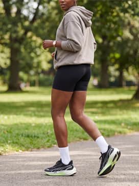 Black high-stretch cycling shorts paired with an oversized neutral-toned graphic hoodie and white crew socks for a post-run athleisure aesthetic.
