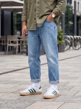 Straight-leg light-wash denim jeans with a rolled cuff, a crisp white heavyweight t-shirt, and an unbuttoned olive green overshirt.