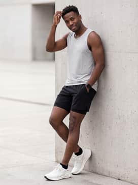 Versablast 4 – Black 7-inch performance running shorts matched with a light grey moisture-wicking tank top and no-show socks for an optimized workout outfit.