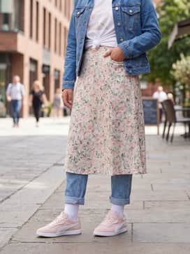 A dainty floral midi skirt in pastel tones paired with a white graphic tee knotted at the waist and a light-wash denim jacket.