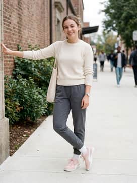 Tapered black high-waisted leggings, white crew socks pulled over the hems, and an oversized sage green sweatshirt for a trendy athleisure vibe.