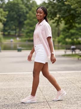 White denim shorts paired with a pastel-striped linen button-down shirt left open over a simple ribbed bodysuit for a breezy summer outfit.