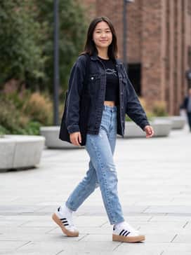 High-waisted mom jeans in a light wash paired with a cropped graphic t-shirt and a denim jacket for a vintage 90s aesthetic.