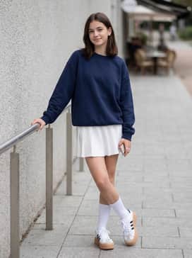 A pleated tennis skirt in navy or white combined with an oversized varsity sweatshirt and tall white crew socks.