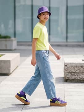 Vl Court Bold Shoes Junior – Light wash wide-leg jeans with a cropped neon yellow tee and a purple bucket hat for a cohesive retro look.