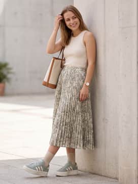 A floral midi skirt in pastel tones with a white ribbed tank top and a structured tote bag.