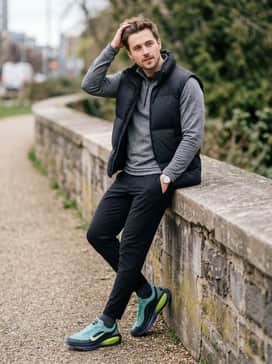 Slim-fit black joggers paired with a heathered grey quarter-zip pullover and an oversized black puffer vest for a post-workout casual vibe.