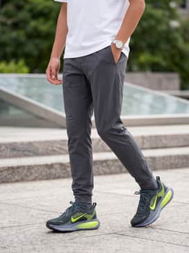 Vomero 18 – A streetwear-inspired ensemble consisting of tapered charcoal tech joggers, a white boxy graphic t-shirt, and a coordinating teal-colored baseball cap.