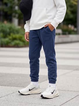 Vomero 18 – Tapered navy blue joggers combined with a crisp white oversized hoodie and a black minimalist baseball cap for a modern streetwear look.