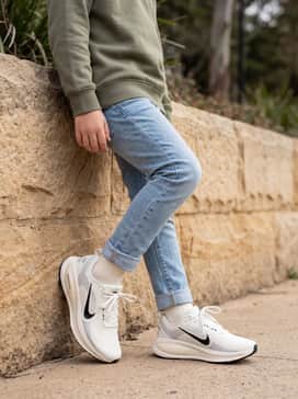 Vomero 18 – Light-wash slim-fit jeans cuffed at the bottom to show off the shoe, worn with a simple olive green crewneck sweatshirt.