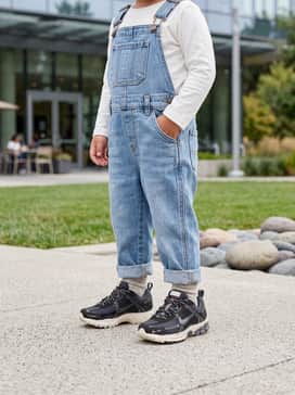 Denim overalls over a simple white long-sleeve tee for a rugged yet stylish playground look.