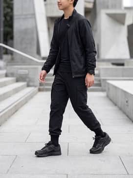 A technical techwear look featuring black water-resistant cargo joggers, a fitted black performance tee, and a lightweight utility windbreaker.