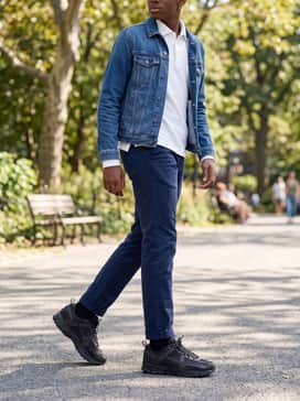 A clean school-ready style using navy blue chino pants, a crisp white long-sleeved polo shirt, and a classic blue denim jacket.