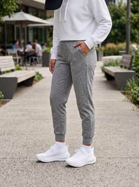 A sleek athleisure look consisting of grey marl tapered joggers, a cropped white hoodie, and a structured black baseball cap for a polished morning coffee run.
