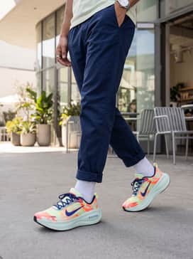 Relaxed-fit navy blue joggers with a tapered ankle, a crisp white oversized graphic hoodie, and a purple baseball cap to pick up the shoe's accent colors for a streetwear vibe.