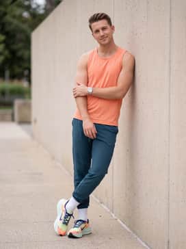 Technical running shorts in a dark teal, paired with a lightweight, perforated bright coral tank top that mirrors the shoe's upper pattern, perfect for warm-weather training.