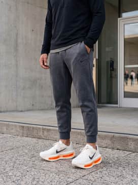 Vomero Premium – Tapered charcoal grey tech-fleece joggers and a sleek black quarter-zip performance pullover for a streamlined, athletic silhouette.