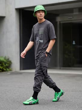 Vs1 Contact Mens Sneakers – Black utility cargo pants featuring tactical straps, paired with a charcoal oversized graphic tee and a matching neon green bucket hat for a cohesive urban look.